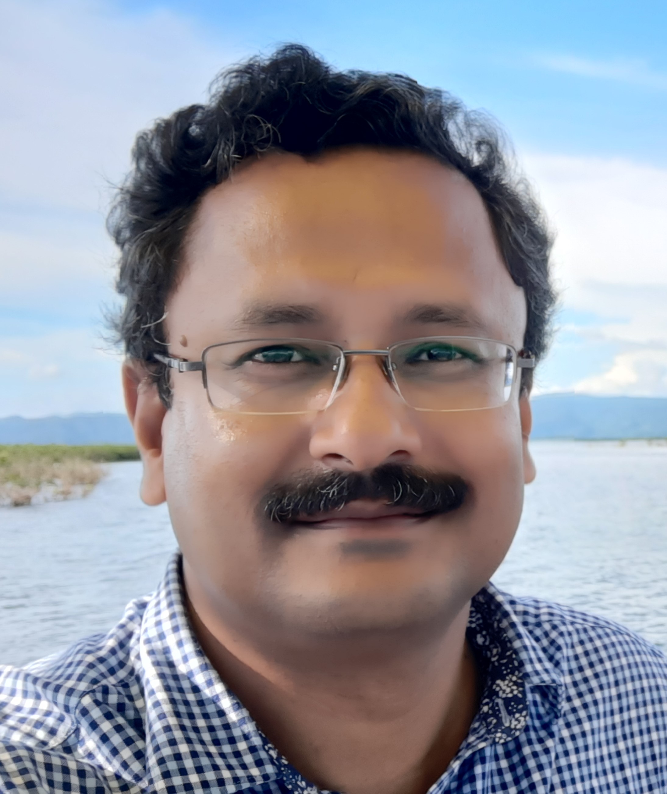 Man wearing a gingham shirt. He wears glasses and has a mustache., Haseeb Irfanullah