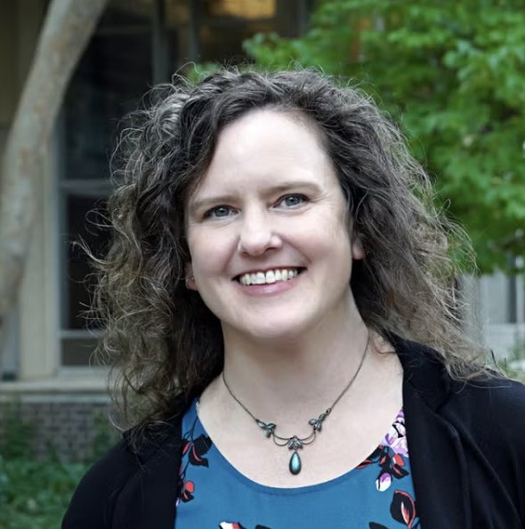 Smiling woman with curly brown hair.