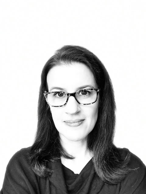 black and white headshot of a woman with spectacles and long dark hair