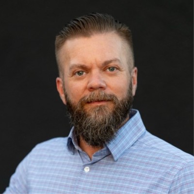 Photo of a bearded man wearing a blue checked shirt.