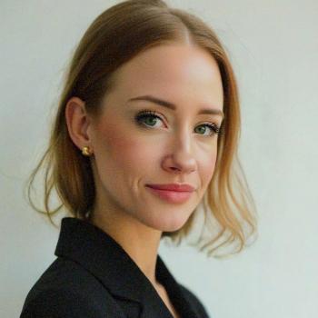 Side profile image of a caucasian woman with short blonde hair, gold earrings, and a black blazer.