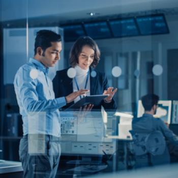 Two human figures in a research lab looking at a tablet.