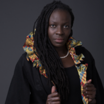 African American woman with long dark hair wearing a black robe adorned with a colorful trim.